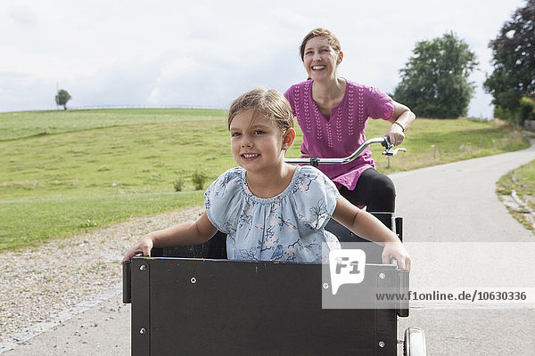 Mother riding bicycle with daughter in trailer