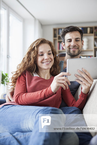 Entspanntes Paar zu Hause auf der Couch mit digitalem Tablett