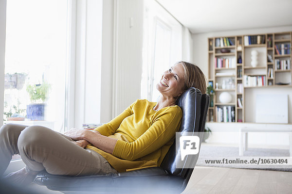 Relaxed woman at home sitting on leather chair