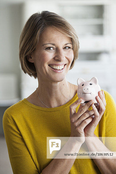 Porträt einer lächelnden Frau mit einem Sparschwein