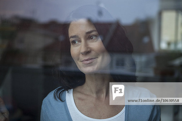 Smiling woman behind windowpane looking out