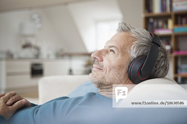 Relaxed man at home wearing headphones listening to music