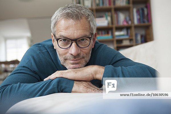 Portrait of mature man at home lying on couch