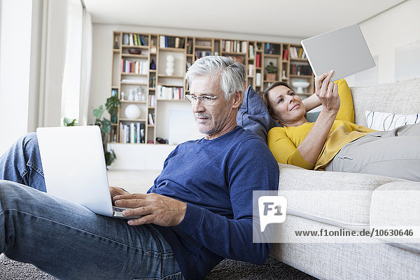 Couple relaxing in the living room with digital devices