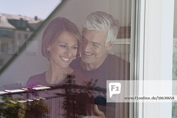 Lächelndes Paar hinter der Fensterscheibe