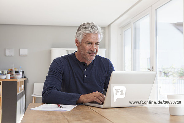 Portrait of mature man using laptop at home