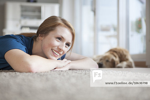 Porträt einer lächelnden jungen Frau  die sich zu Hause auf dem Boden ausruht