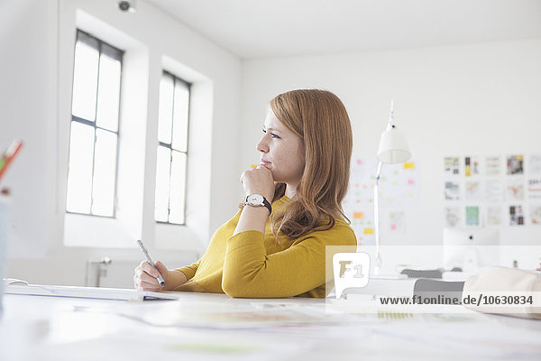 Junge Frau im Büro arbeitet am Schreibtisch
