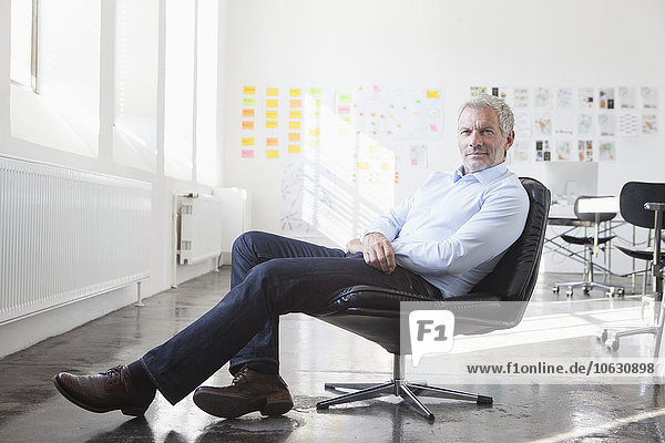 Confident businessman sitting in chair in office
