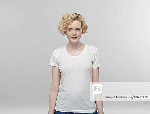 Portrait of blond woman wearing white t-shirt in front of grey background