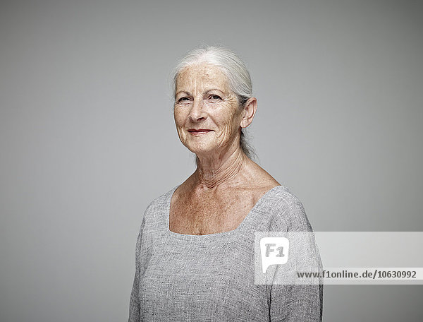 Porträt der lächelnden Seniorin vor grauem Hintergrund