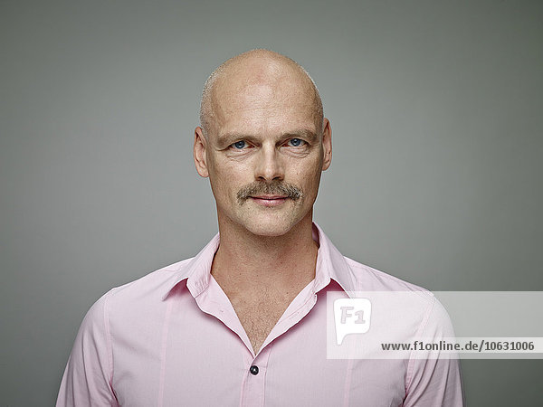 Portrait of bald man with moustache wearing pink shirt