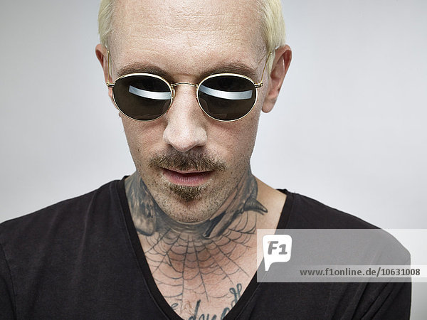 Portrait of man with tattoo and blond dyed hair wearing sunglasses