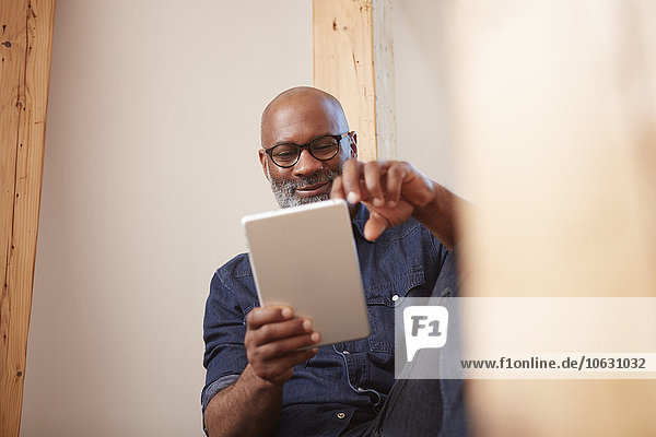 Porträt eines lächelnden Mannes beim Betrachten des digitalen Tabletts
