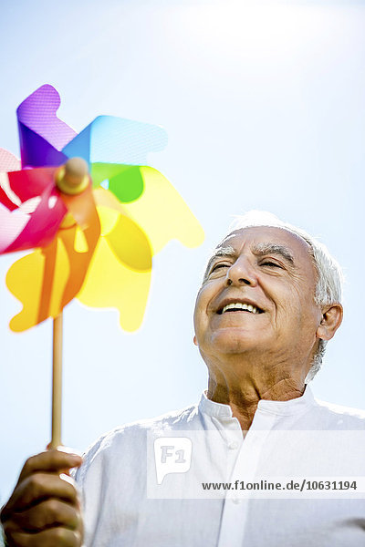 Smiling senior man holding pinwheel outdoors