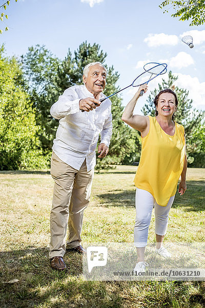 Glückliches älteres Paar auf einer Wiese beim Badmintonspiel