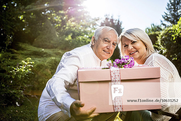 Elderly couple with large present in garden