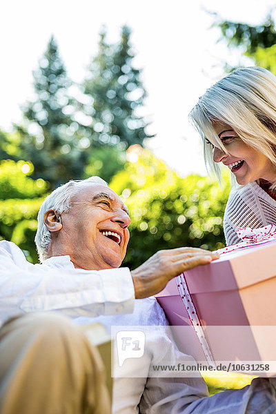 Happy elderly couple with large present outdoors