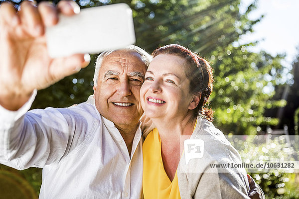 Ein glückliches älteres Paar,  das einen Selfie nach draußen bringt.