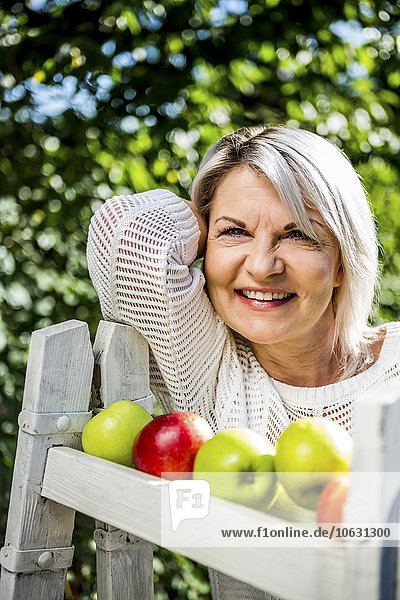 Lächelnde reife Frau mit Äpfeln im Freien