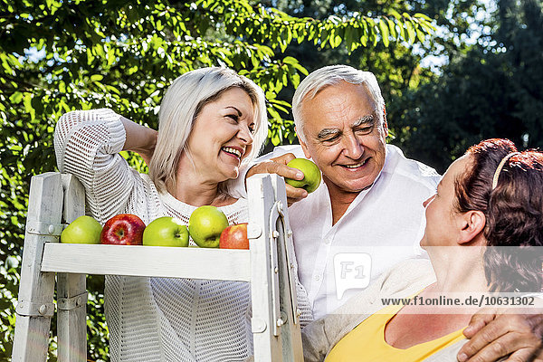 Smiling elderly friends with apples outdoors