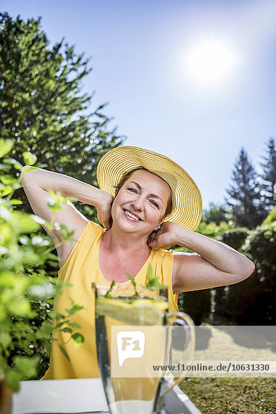 Porträt der lächelnden reifen Frau mit Kräutern im Garten