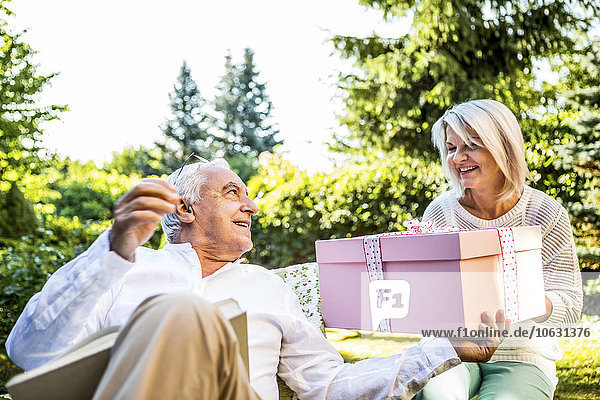 Glückliches älteres Paar mit großem Geschenk im Freien