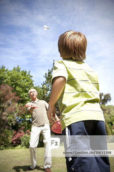 Kleiner Junge  der mit seinem Großvater Badminton spielt.