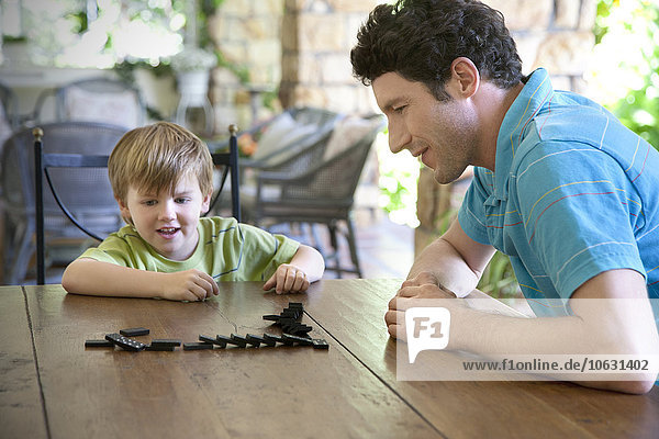 Kleiner Junge spielt mit seinem Vater Domino