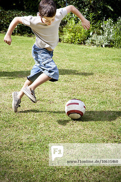 Little boy playing soccer in the garden