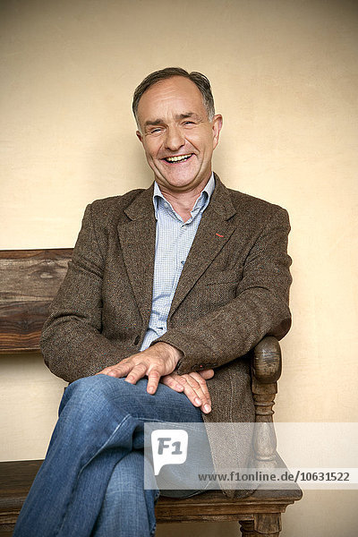 Portrait of laughing mature man sitting on wooden bench