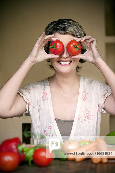Portrait of smiling woman with tomatoes on her eyes