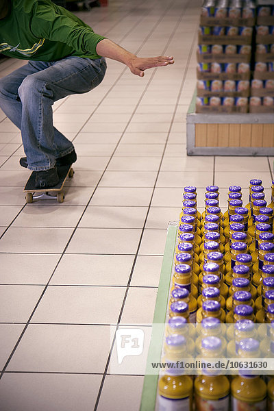 Man skateboarding in a supermarket  partial view