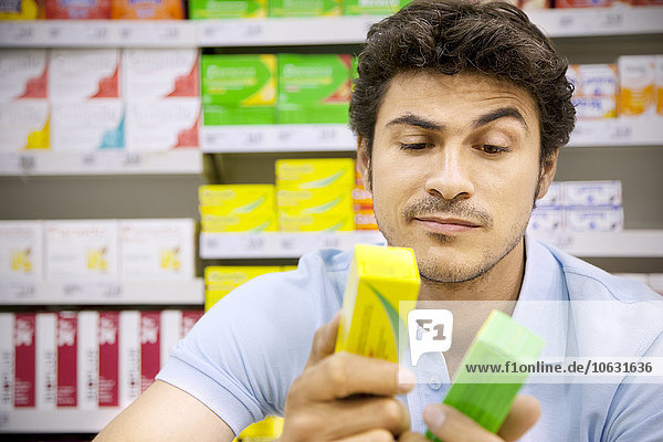 Porträt eines Mannes im Supermarkt im Vergleich zweier Produkte
