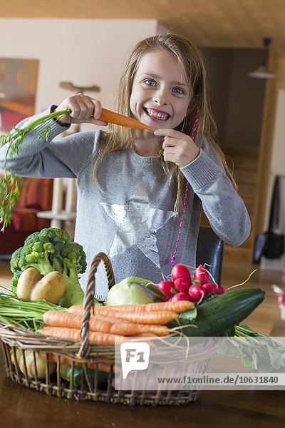 Porträt des Mädchens mit Korb mit frischem Gemüse zu Hause
