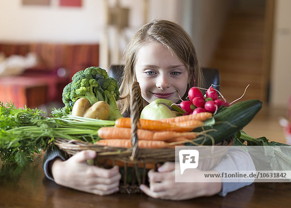 Porträt des lächelnden Mädchens mit Korb mit frischem Gemüse zu Hause