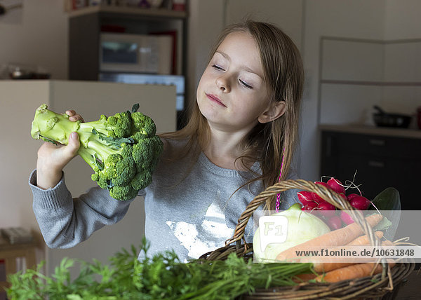 Porträt eines Mädchens mit einem Korb mit frischem Gemüse  das auf Brokkoli blickt