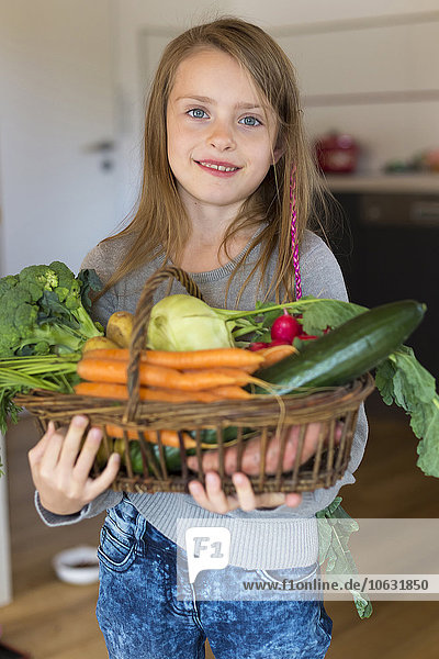 Porträt eines lächelnden Mädchens  das einen Korb mit frischem Gemüse hält.