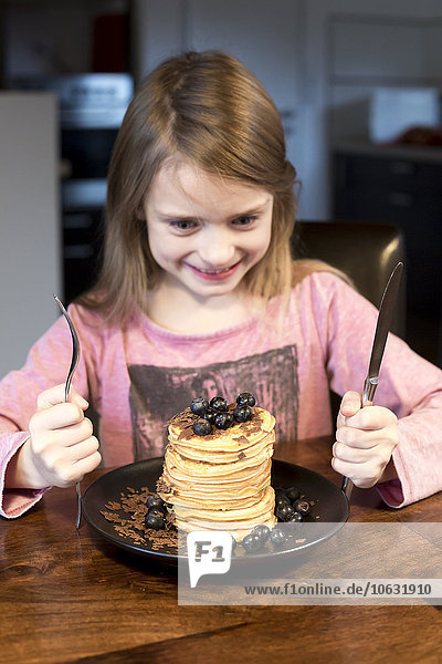 Smiling girl starring at stack of pancakes