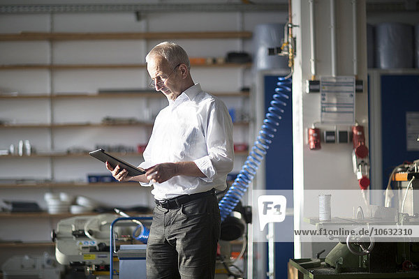 Mann mit digitalem Tablett in einer Werkstatt