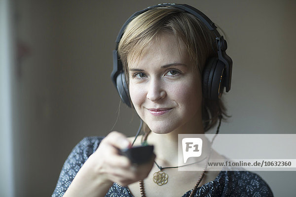 Portrait of smiling young woman with headphones and remote control