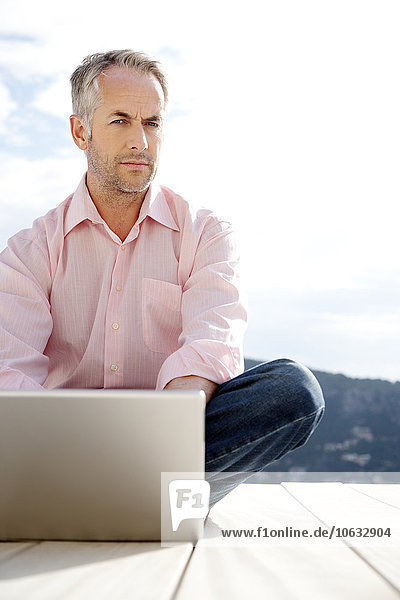 Portrait of serious looking man with laptop