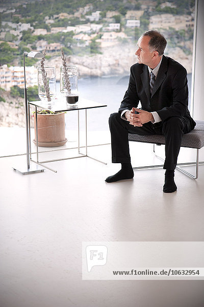 Spain  Mallorca  waiting businessman wearing black suit looking through window