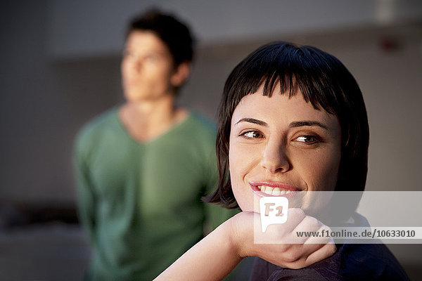 Portrait of smiling young woman with man in background