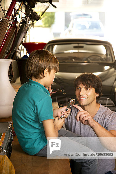 Vater und Sohn in der Garage mit Oldtimer und Werkzeug