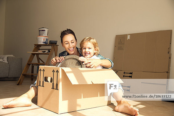 Happy woman with daughter sitting in cardboard box