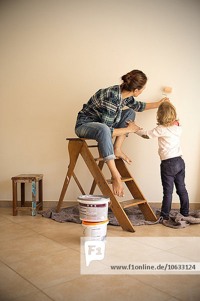 Mother and daughter painting a wall