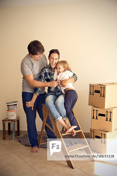 Happy family on step ladder beside cardboard boxes