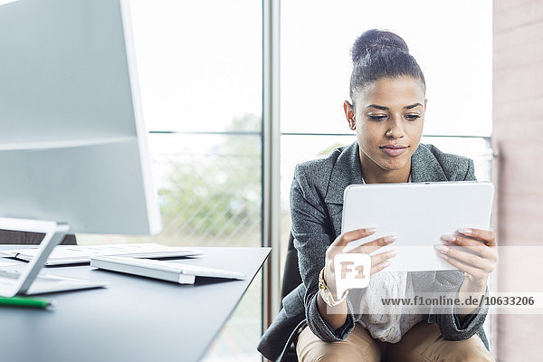 Young woman in office looking on digital tablet