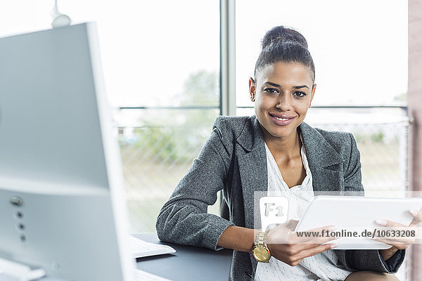 Porträt einer lächelnden jungen Frau im Büro mit digitalem Tablett